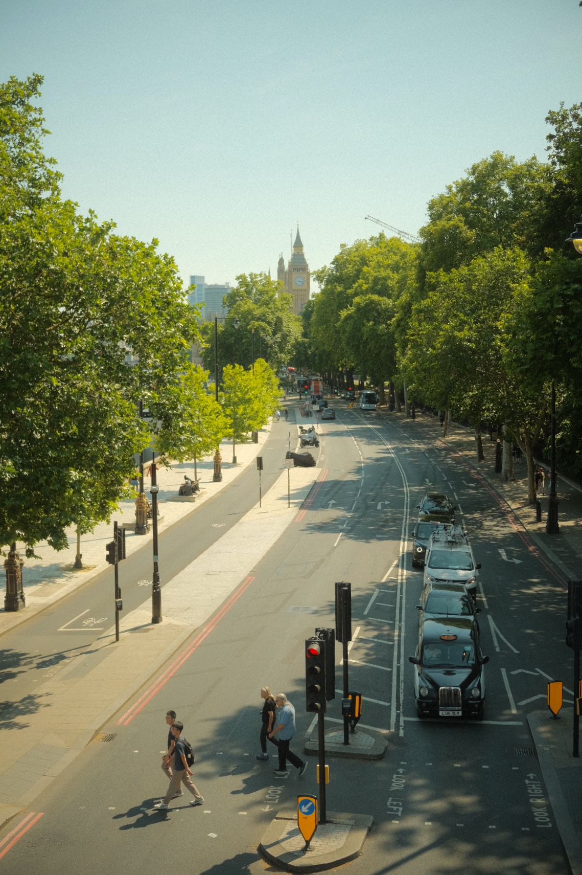 Tree-lined Embankment road with Big Ben in the distance, London.