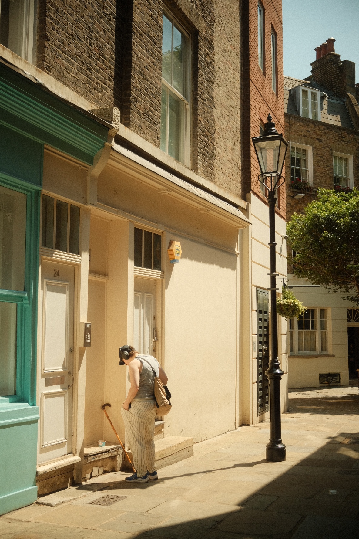 A quiet London side street with a black lamppost and a woman on a doorstep.