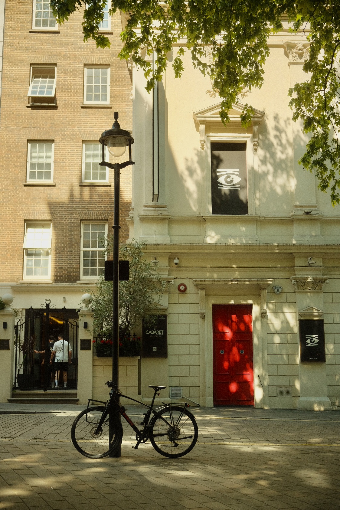 A bicycle parked beside a red door and theater facade in London.