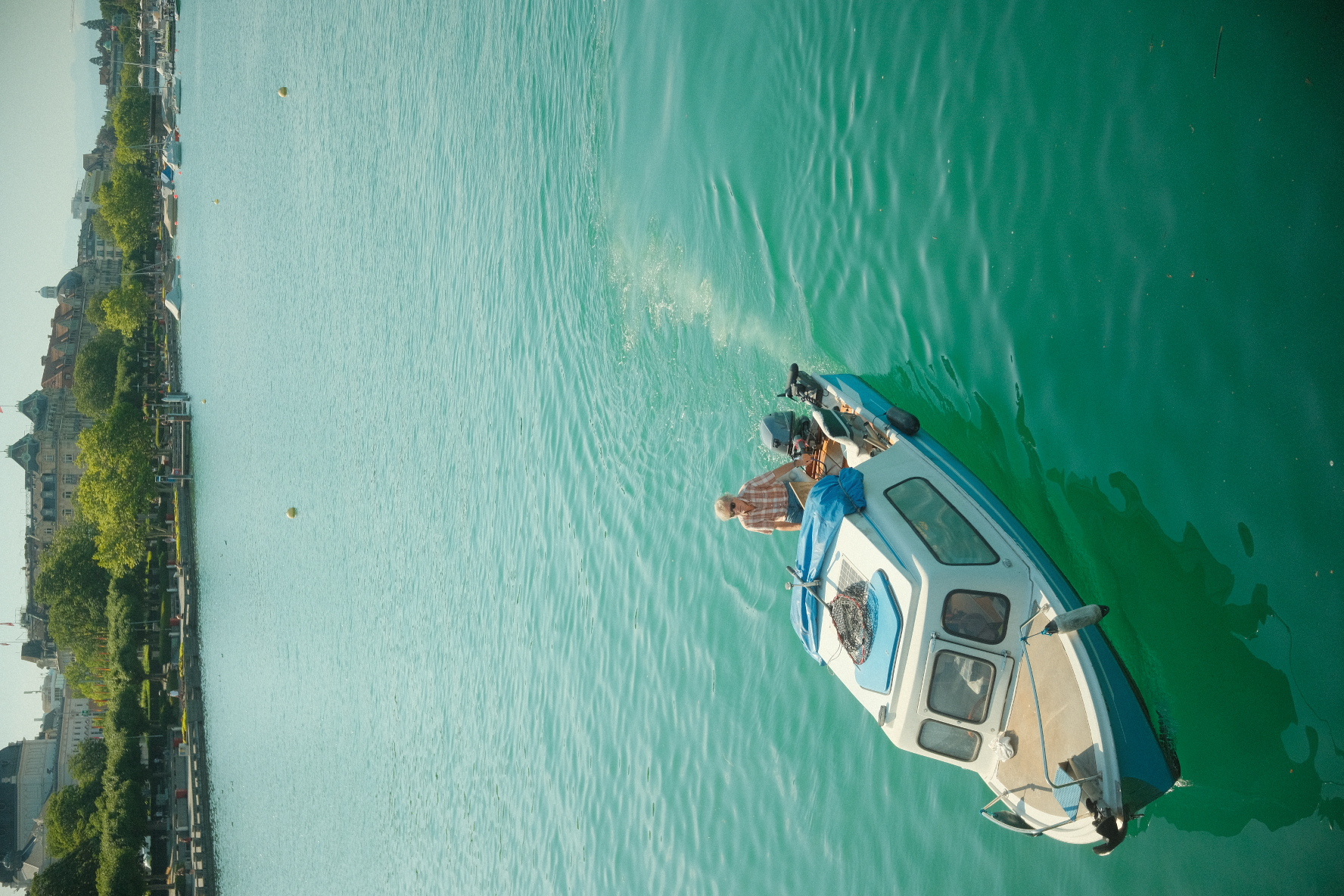 Small boat crossing the turquoise waters of Lake Zurich near the promenade.