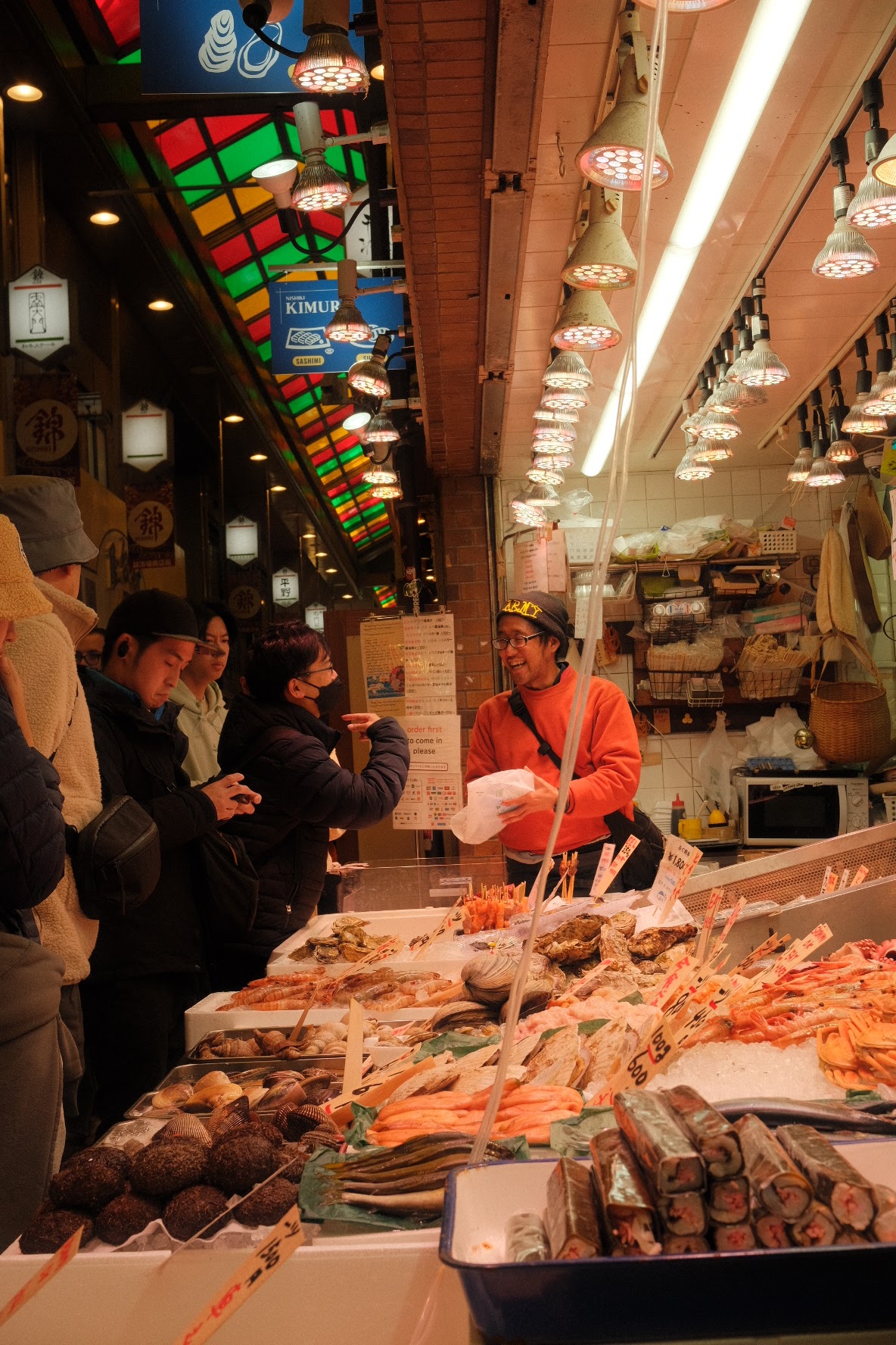 Vendor and customers at a bustling seafood stall inside Kyoto's Nishiki Market.