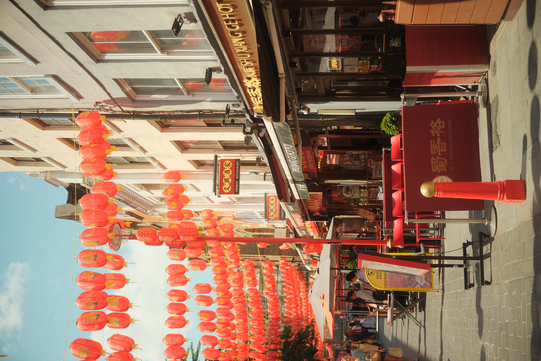Red lanterns strung across a sunny street in London's Chinatown.