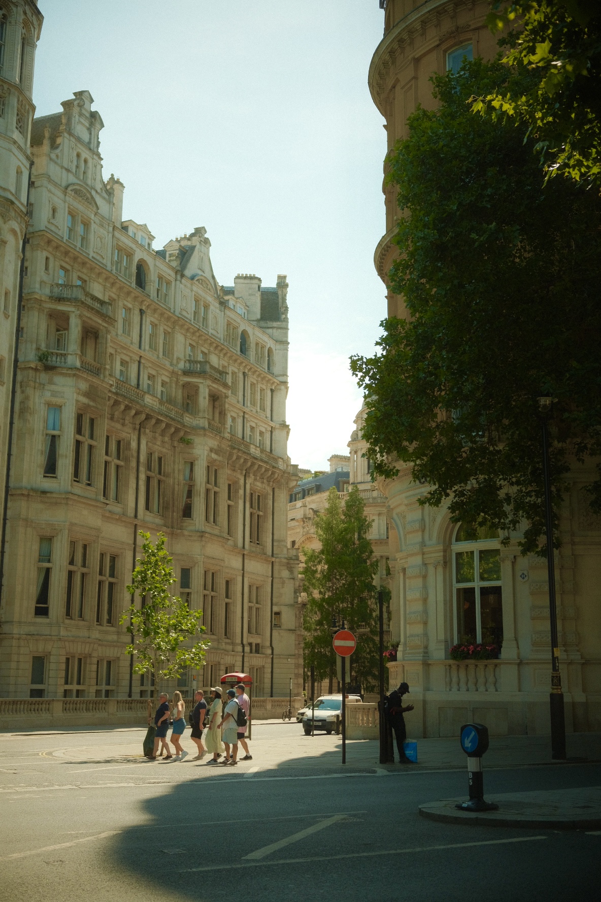 Grand stone buildings and a shaded intersection in central London.