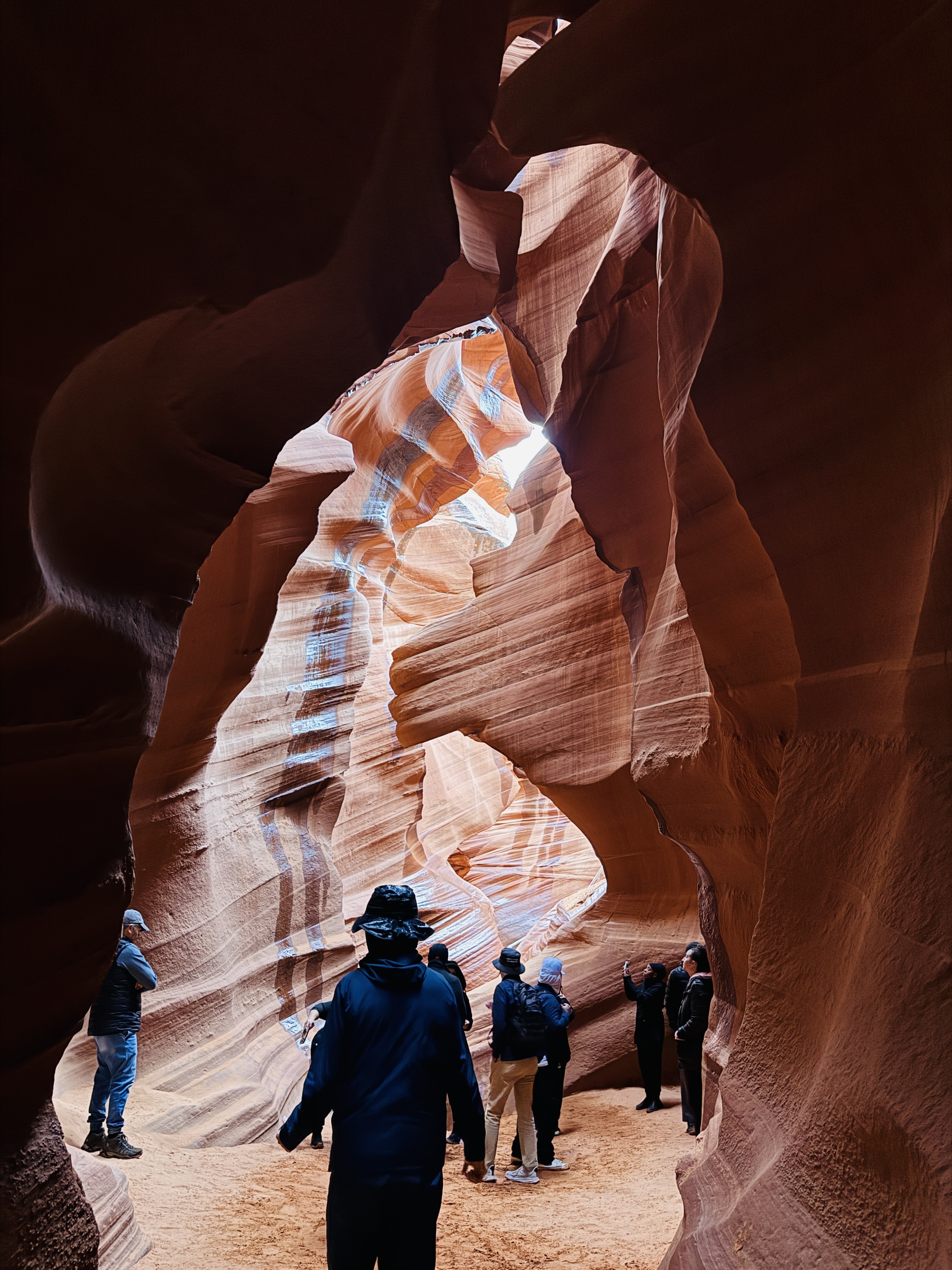 Visitors walking the floor of Antelope Canyon between glowing swirled sandstone walls near Page, Arizona.