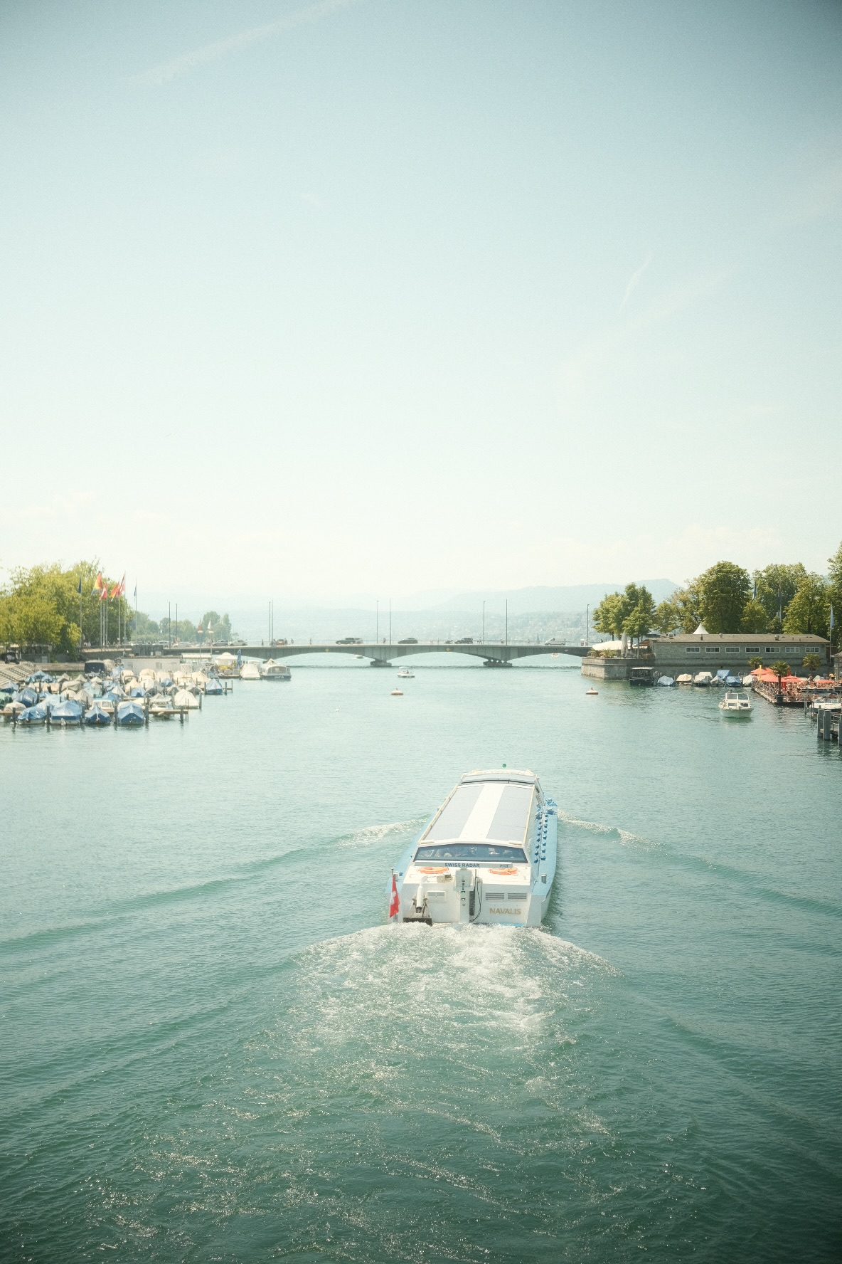 Passenger boat cruising along the Limmat toward a Zurich bridge.