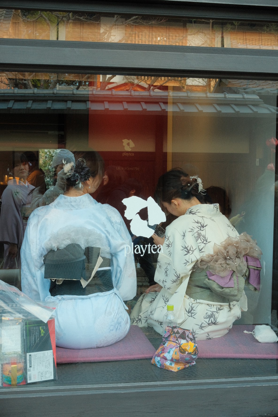 Two women in kimonos seated outside a Kyoto teahouse in Gion.