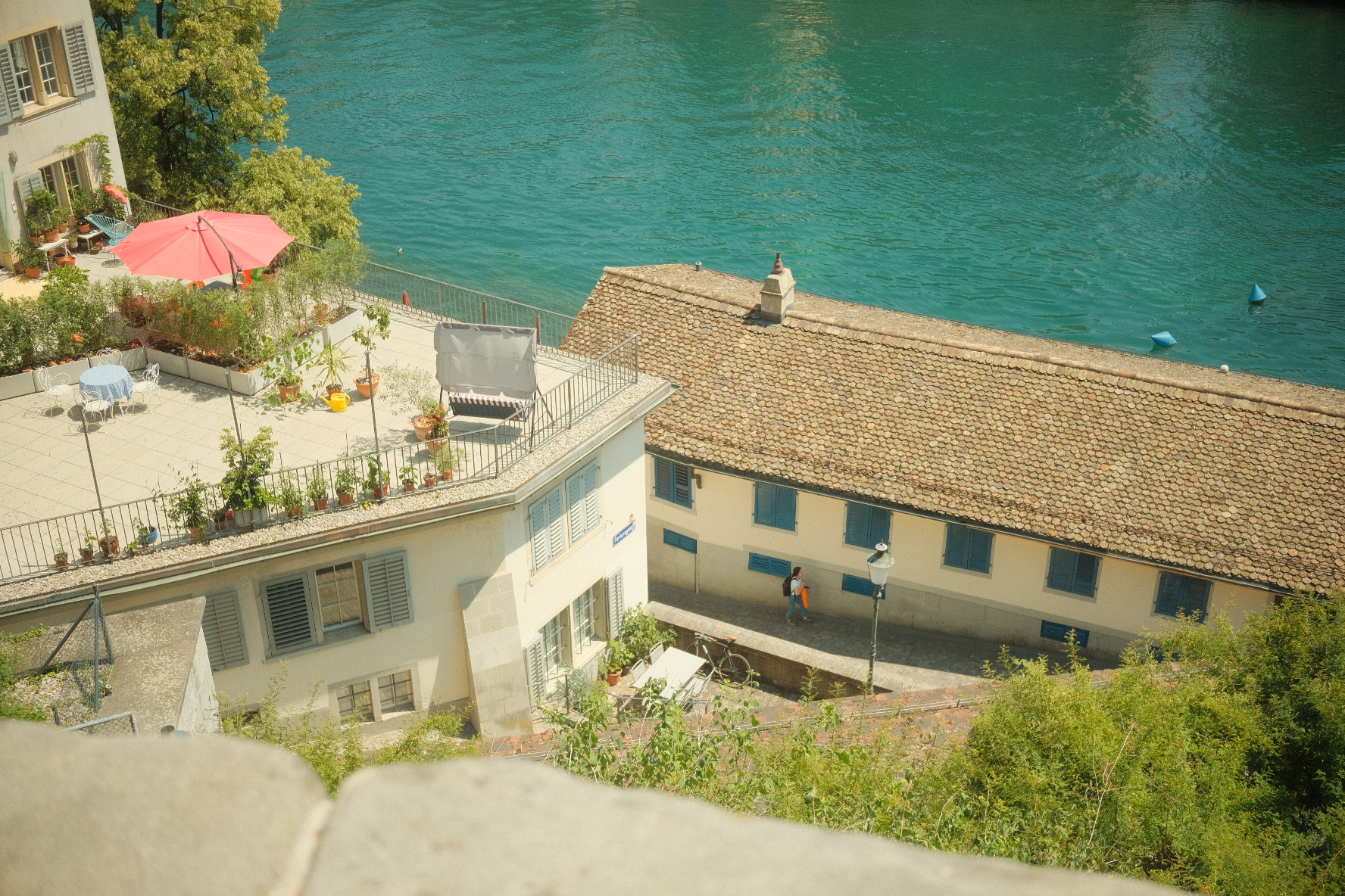 Sunlit rooftop terrace overlooking the Limmat and tiled Zurich rooftops.